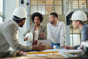A group of engineers and project managers in a technical meeting discussing blueprints, illustrating what is contract staffing for specialized, short-term project needs in the construction and corporate sectors.