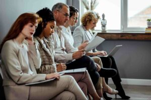 Employees reviewing resumes and job applications while evaluating staffing agency vs recruitment firm hiring options in an office setting.