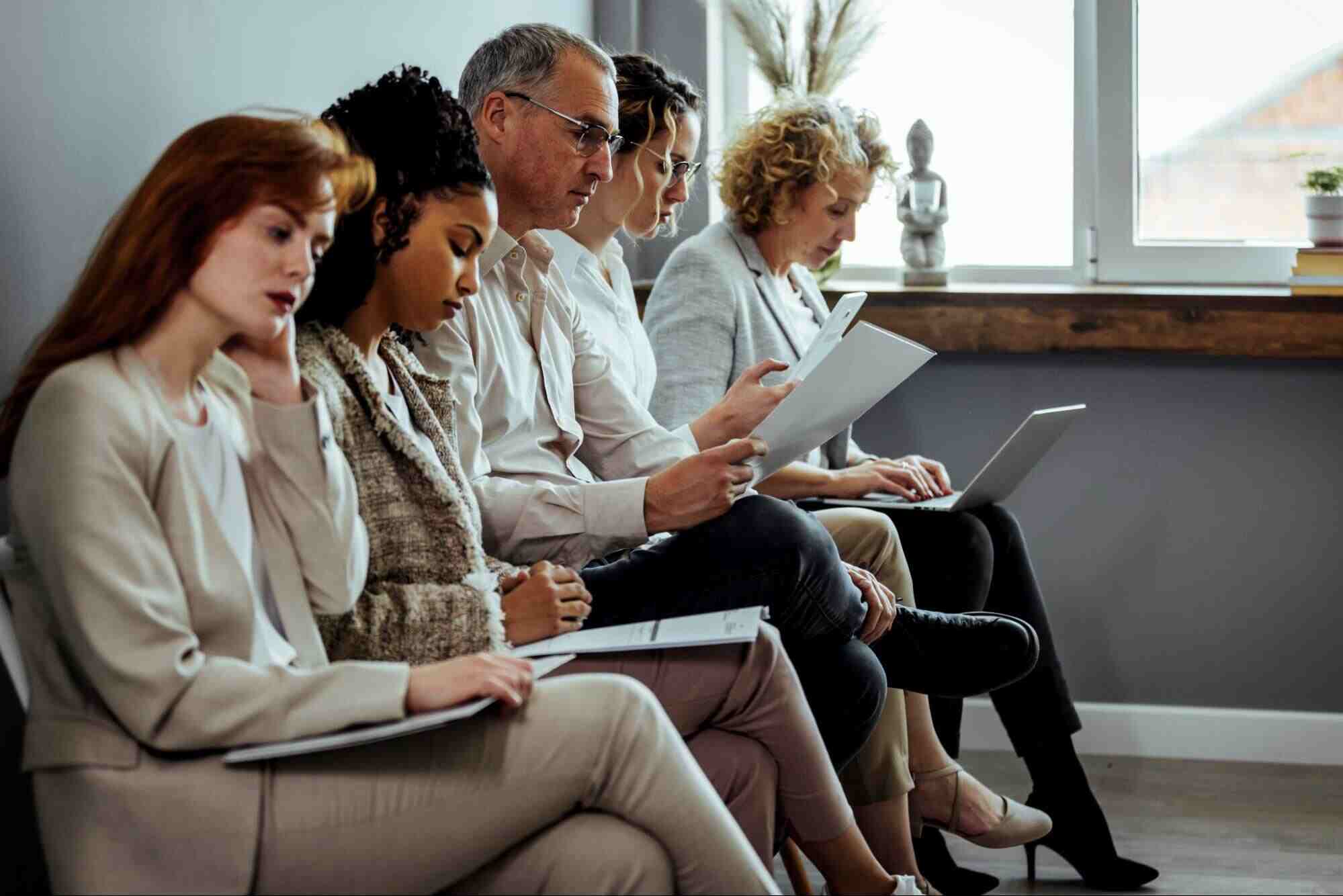 Employees reviewing resumes and job applications while evaluating staffing agency vs recruitment firm hiring options in an office setting.