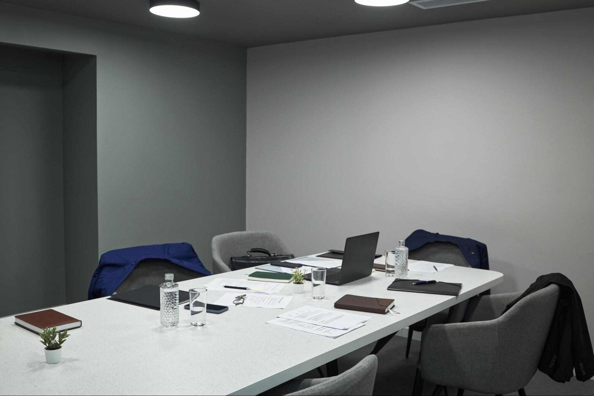 Modern office meeting room with several empty chairs around a conference table, illustrating the cost of being understaffed through unfilled workspaces and reduced team capacity.