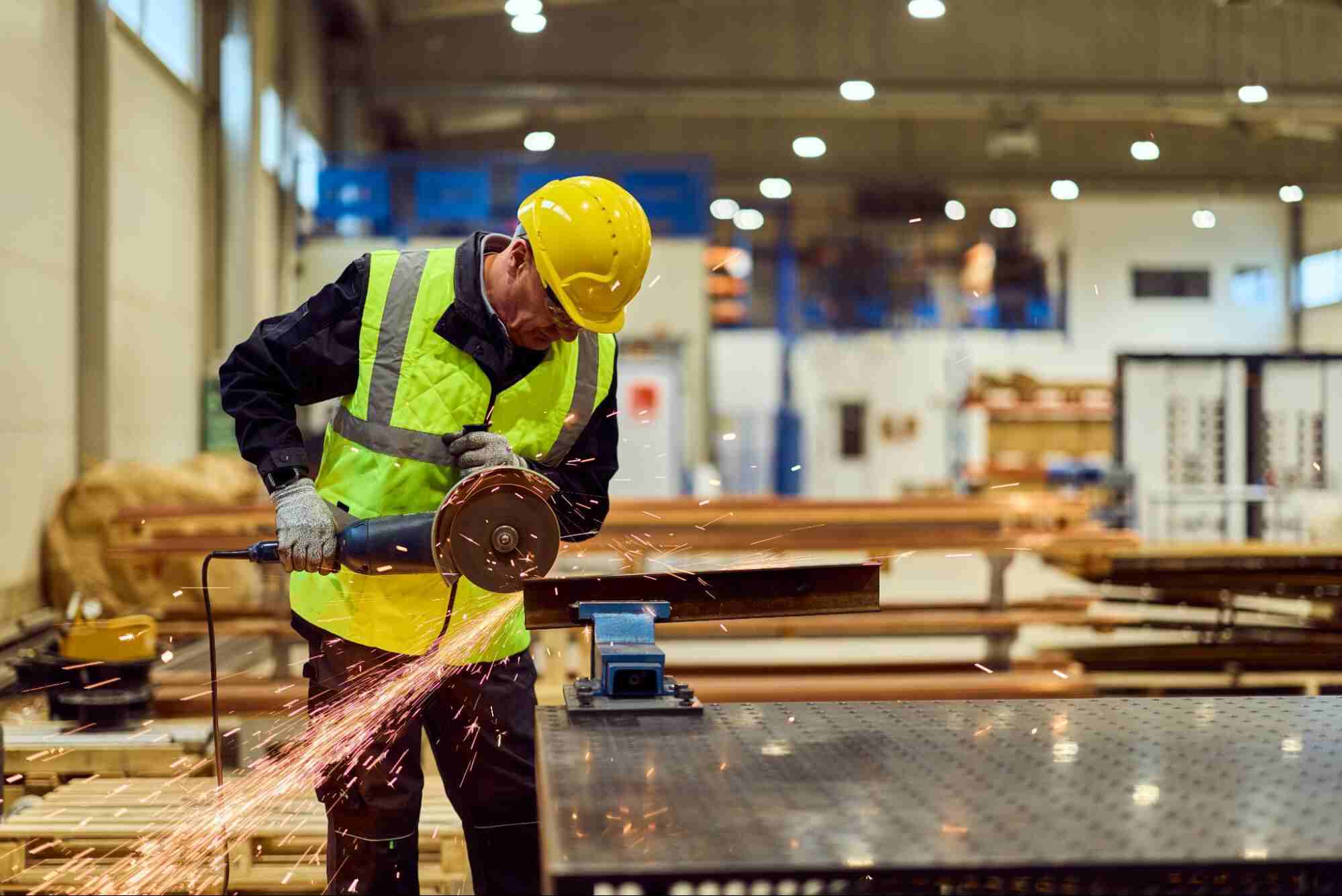 Skilled worker cutting metal in a manufacturing facility during skilled labour shortages.